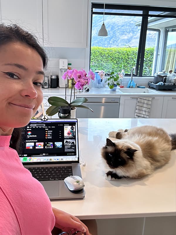 Girl working with laptop on the table and cat by the side