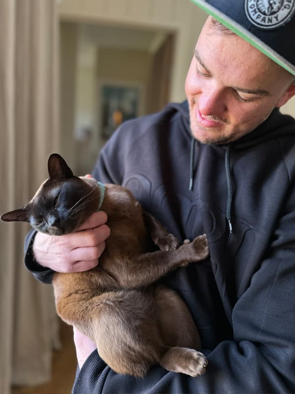 Man hugging a brown cat